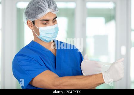 Ein männlicher Arzt zieht Latexhandschuhe aus Stockfoto