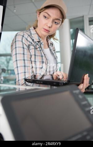 Junge Reparaturfrau, die Drucker repariert Stockfoto