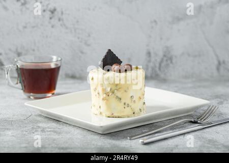 Ein-Personen-Minikuchen mit Pistazien und weißer Schokolade auf einem weißen Porzellanteller Stockfoto