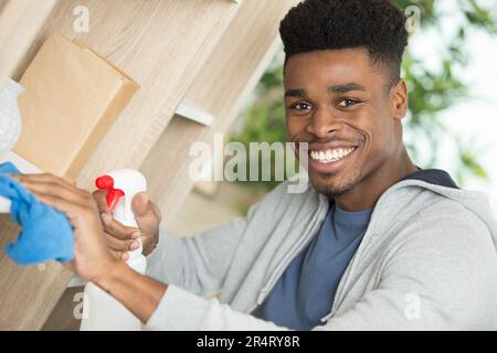 Porträt eines glücklichen jungen Mannes, der Küchenarbeitsplatte putzt Stockfoto