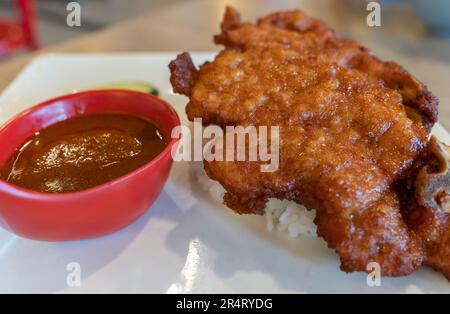 Nahaufnahme des Schweinekoteletts mit Reis, Gurke und Sambal-Sauce. Stockfoto