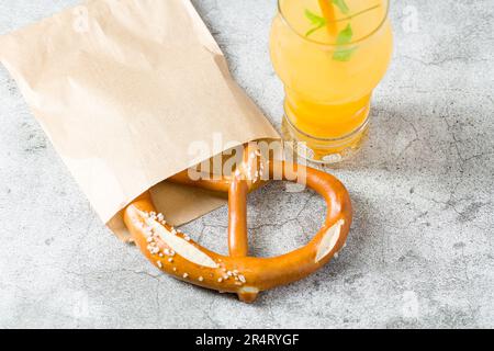 Brezel in Geschenkpapier eingewickelt mit einem Getränk daneben auf einem Steintisch Stockfoto