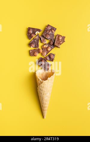 Eiskrem und Schokoriegel mit Nüssen auf gelbem Hintergrund. Draufsicht. Stockfoto