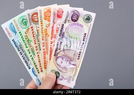 Altes philippinisches Geld - Peso in der Hand auf grauem Hintergrund Stockfoto