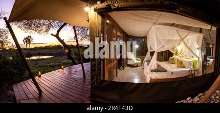 Panoramabild eines beleuchteten Zelts bei Sonnenuntergang im Onguma Zeltlager, Onguma Wildreservat, Namibia, Afrika Stockfoto