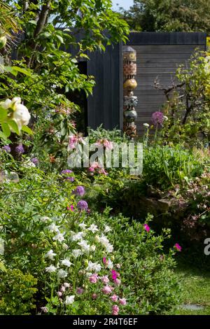 Ein dreckiger Bettkopfgarten in Pinner, London mit Steingarten. Aquilegienblüten im Vordergrund. Eco Garden Studio mit schwarzer und Zedernverkleidung. Stockfoto