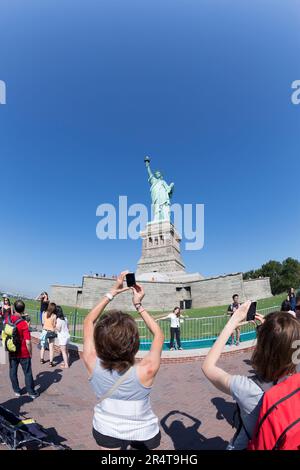 WIR, New York, Leute, die Fotos von der Freiheitsstatue mit dem Telefon machen. Stockfoto