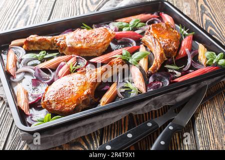 Gesundes und leckeres Essen gebackene Schweinekoteletts mit roten Zwiebeln, Kräutern und Rhabarber Nahaufnahme auf einem Backblech auf dem Tisch. Horizontal Stockfoto