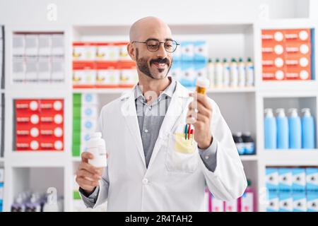 Junger hispanic-Mann Apotheker hält Pillen Flaschen in der Apotheke Stockfoto