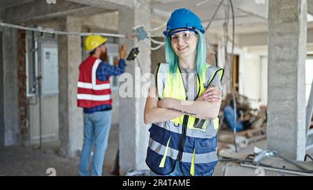 Mann und Frau, die auf der Baustelle mit gedrückten Armen stehen Stockfoto