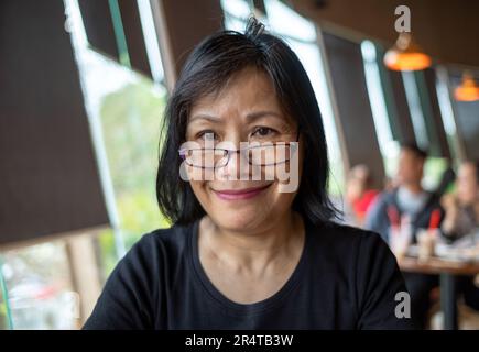 Eine vietnamesische Frau mit Brille lächelt, während sie in die Kamera schaut, Danang, Vietnam Stockfoto