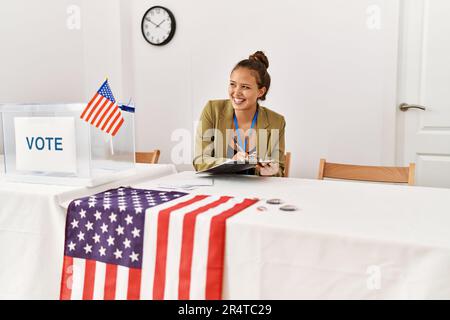 Junge schöne hispanische Frau Wahltisch Präsident schriftlich auf Zwischenablage an Wahlhochschule Stockfoto