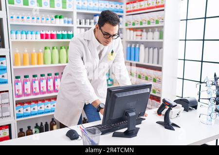 Junger hispanischer Apotheker mit Computer in der Apotheke Stockfoto
