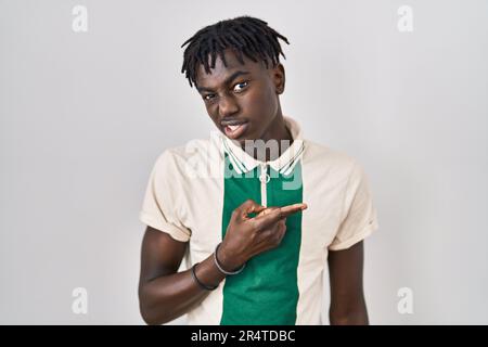 Ein afrikanischer Mann mit Dreadlocks, der über einem isolierten Hintergrund steht und zur Seite zeigt, besorgt und nervös mit dem Zeigefinger, besorgt und überraschter Ausdruck Stockfoto