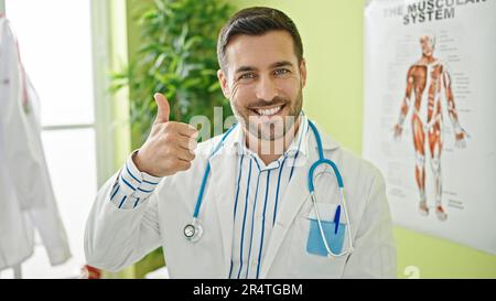 Junger hispanischer Arzt, der in der Klinik Daumen hoch hält Stockfoto