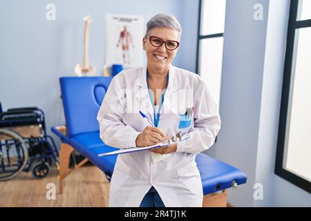 Frau im mittleren Alter, Physiotherapeutin, die in der Reha-Klinik auf die Zwischenablage schreibt Stockfoto