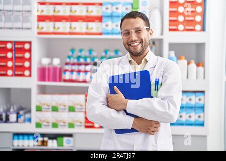 Junger Mann Apotheker hält Zwischenablage in der Apotheke Stockfoto