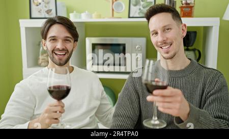 Zwei Männer, die selbstbewusst ein Glas Wein im Speisesaal trinken Stockfoto