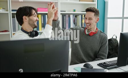 Zwei männliche Studenten studieren High Five an der Bibliotheksuniversität Stockfoto