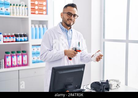 Junger hispanischer Mann Apotheker Scannen Pillen Flasche in der Apotheke Stockfoto