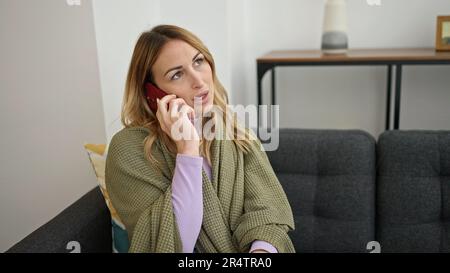 Junge, wunderschöne hispanische Frau, die sich krank fühlt und mit dem Arzt zu Hause telefoniert Stockfoto