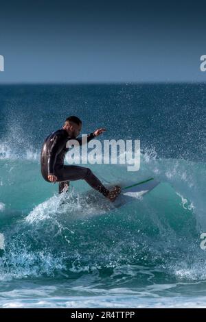 Spektakuläre Surfaktion als männlicher Surfer reitet auf einer Welle im Fistral in Newquay in Cornwall in England in Großbritannien. Stockfoto