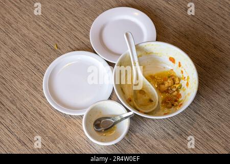 Dreckige Schüssel mit Suppenresten mit Löffel und Tellern auf Holztisch. Draufsicht mit Kopierbereich für Text. Stockfoto