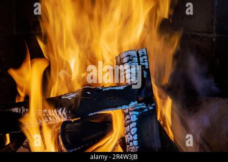 Wenn die Temperaturen im Winter sinken, wird der traditionelle ländliche Kamin zum Herzstück des Zuhauses mit einem hellen Holzfeuer. Stockfoto