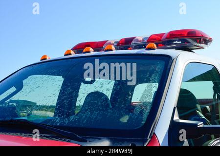 Ein roter Feuerwehrauto mit Lichtbalken auf dem Dach. Die Lichter sind rot, orange und weiß. Der Rettungswagen hat ein weißes Dach. Stockfoto