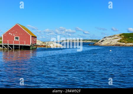 Ein malerisches Fischerdorf am Rande einer felsigen Küste. Die Lagergebäude sind rot, grün und blau gefärbt. Der Sommerhimmel ist blau. Stockfoto