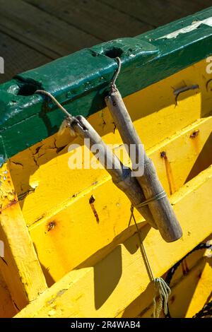 Nach unten sehen Sie ein gelbes Holzboot mit dunkelgrüner Verzierung und sehen einen Holzdido und ein Seil. Das Boot ist an der Anlegestelle mit einem Seil befestigt. Das Wasser Stockfoto
