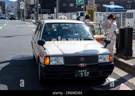 Kyoto, Japan. 7. März 2023. Frauen in traditionellen japanischen Kimonos steigen im Urlaub in ein Taxi. Kyoto (ä°¬éƒ½) ist eine historische Großstadt Japans, reich an kulturellem Erbe und traditionellem Charme. Bekannt für seine berühmten Tempel, malerischen Gärten und historischen Wahrzeichen wie Kinkaku-ji und Fushimi Inari Taisha, bietet Kyoto einen Einblick in Japans Vergangenheit. Die lebhaften Festivals, die exquisite Küche und die ruhige Atmosphäre begeistern Besucher aus der ganzen Welt. Es ist ein geschäftiger Knotenpunkt für die japanische Tourismusbranche und beherbergt viele Unternehmen wie Nintendo. Japan hat eine rückläufige Bevölkerung und Stockfoto