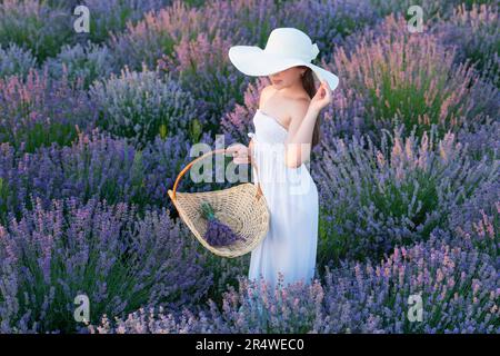 Teenager mit Lavendel auf der Wiese. Teenager-Mädchen mit Lavendelblume, die auf dem Feld steht. Teenager mit Lavendel und Blumenstrauß. Teenager-Mädchen Stockfoto