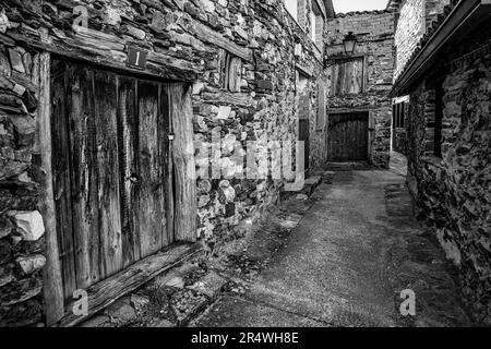 Alte Steinhäuser bilden eine enge Gasse in einem alten Dorf von Madrid, Puebla de la Sierra. Stockfoto