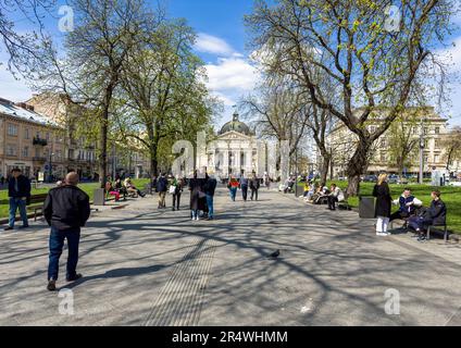 Lemberg, Ukraine - Mai 2023: Menschen, die an sonnigen Tagen im Park in der Nähe des Opernhaustheaters spazieren. Wunderschönes Stadtleben in der Stadt Lemberg in der Ukraine Stockfoto