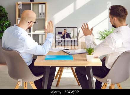 Zwei Geschäftsleute, die während einer Videokonferenz im Büro mit Kollegen sprechen Stockfoto