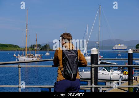 Oban, Schottland, Großbritannien. 30. Mai 2023 Herrliches warmes und sonniges Wetter in Oban mit Einheimischen und Besuchern, die das Beste aus der Feiertagswoche machen, werden die sonnigen Bedingungen voraussichtlich über das Wochenende andauern. Luxuriöser Kreuzfahrtschiff Spirit of Adventure in der Bucht mit Shuttlebooten, die Passagiere nach Oban bringen. Blick auf die Berge auf der Insel Mull. Kredit: Craig Brown/Alamy Live News Stockfoto