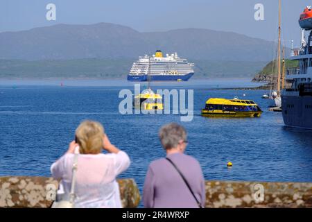 Oban, Schottland, Großbritannien. 30. Mai 2023 Herrliches warmes und sonniges Wetter in Oban mit Einheimischen und Besuchern, die das Beste aus der Feiertagswoche machen, werden die sonnigen Bedingungen voraussichtlich über das Wochenende andauern. Luxuriöser Kreuzfahrtschiff Spirit of Adventure in der Bucht mit Shuttlebooten, die Passagiere nach Oban bringen. Blick auf die Berge auf der Insel Mull. Kredit: Craig Brown/Alamy Live News Stockfoto