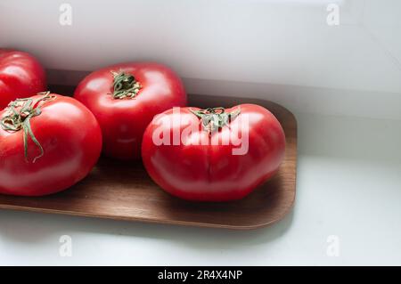 Köstliche rote reife Sommertomaten aus Rindfleisch auf einem Holztablett Stockfoto