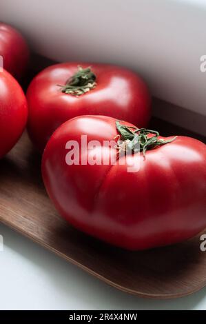 Köstliche rote reife Sommertomaten aus Rindfleisch auf einem Holztablett Stockfoto