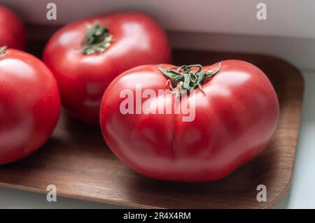 Köstliche rote reife Sommertomaten aus Rindfleisch auf einem Holztablett Stockfoto