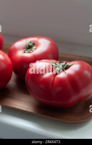 Köstliche rote reife Sommertomaten aus Rindfleisch auf einem Holztablett Stockfoto