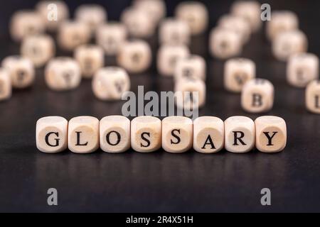Glossar - Wort aus Holzblöcken mit Buchstaben, alphabetische Liste mit Wortbedeutungen Wörterbuch Glossarkonzept, zufällige Buchstaben um, Draufsicht ein Stockfoto