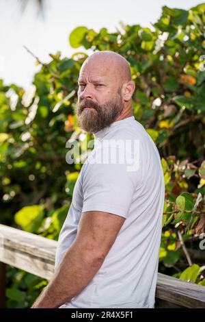 Ein bärtiger Mann, der in einem weißen Hemd posiert Stockfoto