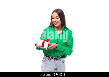 Porträt einer glücklichen, schlanken, braunäugigen, brünetten Frau in einem grünen Hemd, die ein Geburtstagsgeschenk bekam Stockfoto