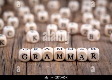 Das Wort Grammatik Holzwürfel mit verbrannten Buchstaben, Grammatikstudien verschiedener Sprachen, hölzerne Hintergrundansicht von oben, verstreute Würfel um zufällig l Stockfoto