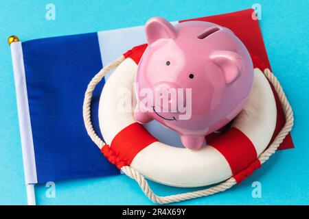 Sparschwein, Rettungsring und Flagge auf blauem Hintergrund, ein Konzept zum Thema Rettung der französischen Wirtschaft Stockfoto