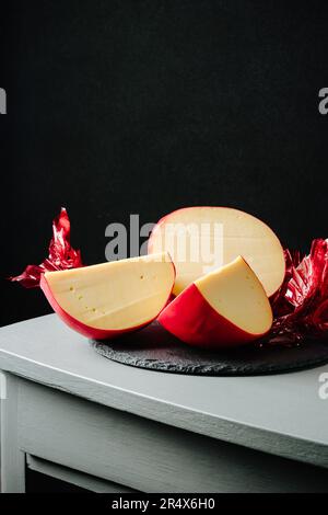 In Scheiben geschnittener Edamskäse, mit roter Wachsschicht bedeckt. Stockfoto