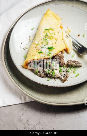 Omelette mit Morchelpilzen und Käse in einer cremigen Sauce mit Kräutern. Stockfoto