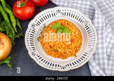 Traditioneller türkischer Bulgur-Pilaf mit Tomatensoße auf dem Teller (türkischer Name; Meyhane pilavi) Stockfoto